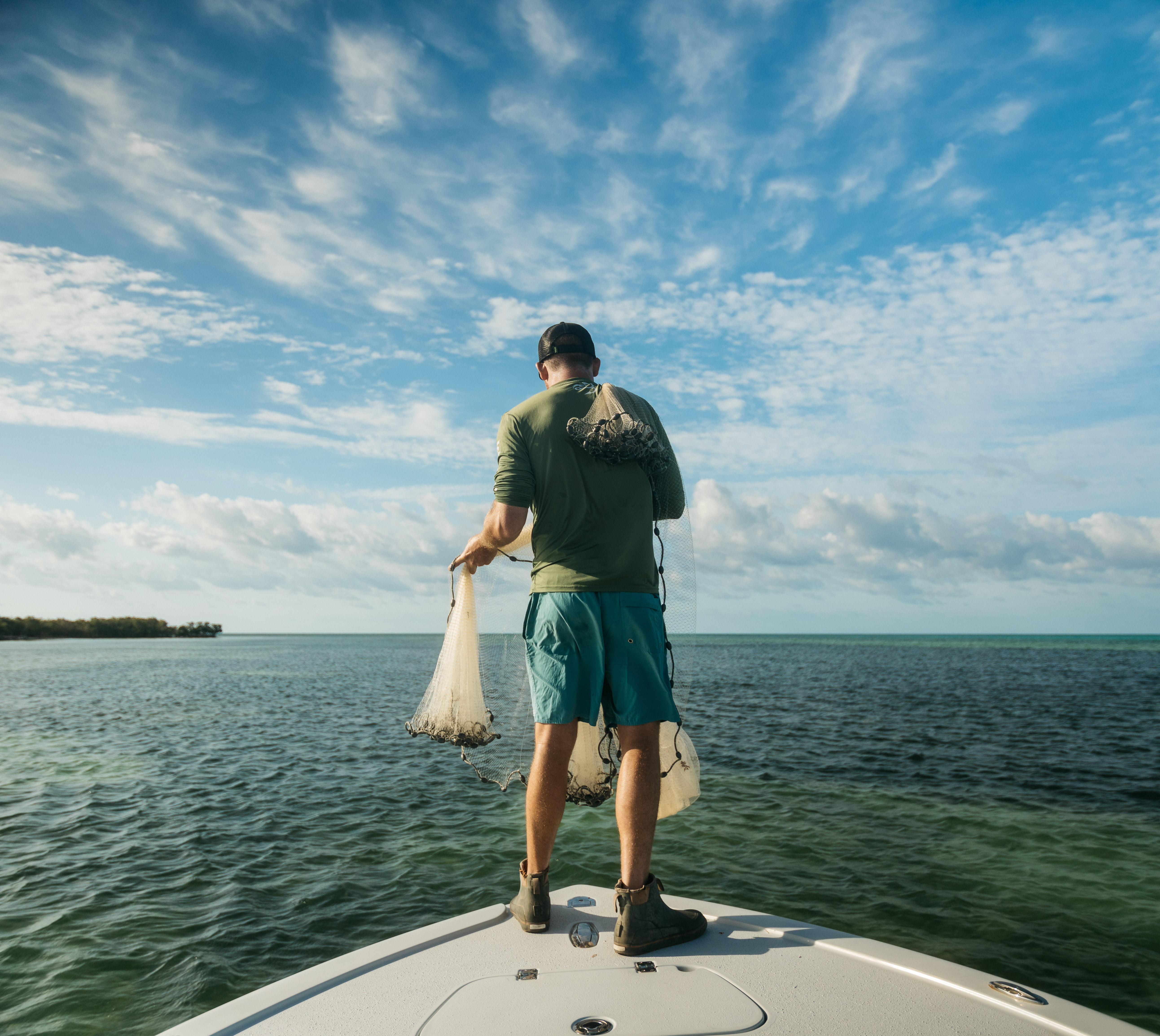 kyff Outdoors photographer on fishing boat bow with cast net — offshore fishing photography